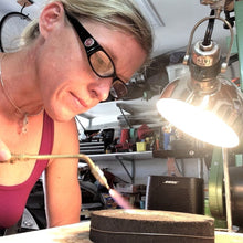 Load image into Gallery viewer, Sarah Miller artist at bench using torch Seaside Harmony Jewelry