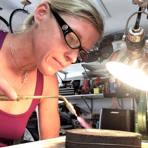 Sarah Miller artist at bench using torch Seaside Harmony Jewelry