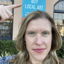 Load image into Gallery viewer, Sarah Miller artist in front of buy local art sign